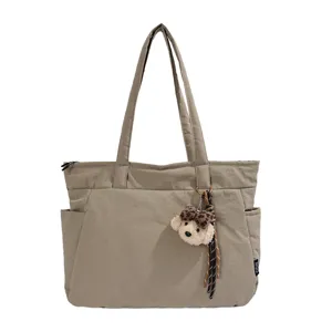 Grand cabas beige en nylon, avec fermeture zippée, poches latérales, longues anses et porte-clés ours