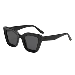 Lunettes de soleil noires à monture œil-de-chat, verres gris foncé et rivets dorés, vues de biais