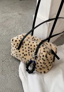 Beige Plüschfläche mit schwarzen Punkten, Reißverschluss und schwarzem Riemen mit Perlenanhänger