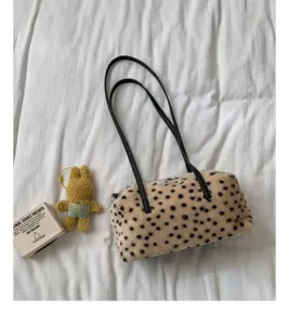 Beige Plüschtasche mit schwarzen Kunstledergriffen, flach auf weißer Bettwäsche arrangiert