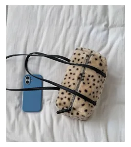 Draufsicht auf eine gepunktete Plüschtasche in Zylinderform mit schwarzem Riemen und Reißverschluss