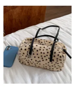 Detail einer gepunkteten Plüschtasche mit schwarzen Henkeln, Herzanhänger und Reißverschluss