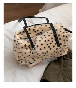 Schrägansicht einer gefleckten Plüschtasche mit schwarzen Henkeln, Metallherz und Reißverschluss