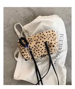 Flache Ansicht einer beigen Plüschtasche mit schwarzen Punkten, Perlengriff und langem Schulterriemen