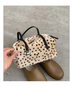 Nahaufnahme einer Plüschtasche mit Leopardenmuster, schwarzen Henkeln und silbernem Herzanhänger
