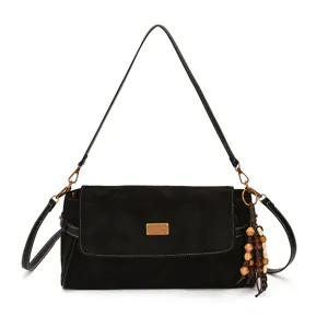 Sac noir à rabat, plaque dorée, bandoulière surpiquée et pompon en perles de bois, sur fond blanc