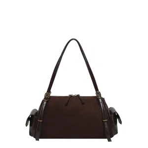 Studio view of a brown suede-textured bag with zip closure, side flap pockets and a long strap