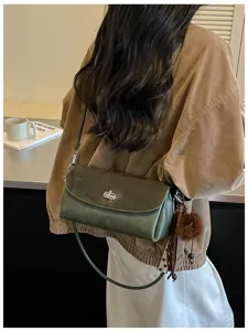 Vista trasera de una modelo con bolso verde bicolor, cierre metálico y un colgante de pelo suave
