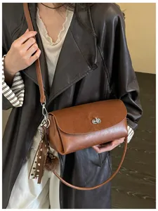 Bolso marrón con solapa, visto en uso, cierre plateado, pañuelo decorativo y correa desmontable