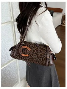 Model wearing a leopard-print shoulder bag with brown leather trim and a wooden C-shaped clasp