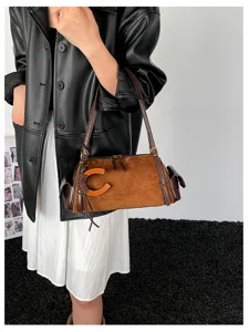 Brown suede-look bag with C-shaped accent and braided knot, shown on a model with leather straps