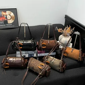 Cylindrical shoulder bags in varied finishes, including leopard print, with wooden C-shaped accents