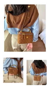 Vista de un bolso marrón acolchado llevado al hombro, con cadena dorada y asa superior curva
