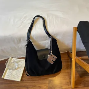 Schwarze Wildleder-Schultertasche mit Klappe, Lederriemen und braunem Lederanhänger