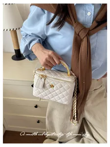 Bolso acolchado color crema llevado en la mano y cruzado, con asa y cadena de acabado dorado