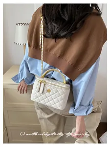 Bolso blanco acolchado con cadena dorada y adorno floral, llevado en una escena cotidiana