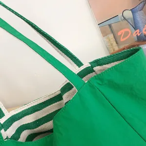 Primer plano del bolso tote verde con asas dobles tejidas a rayas verdes y blancas, y costuras