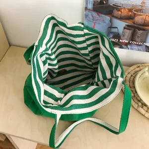 Vista superior del bolso tote abierto, con forro de rayas verdes y blancas y asas verdes