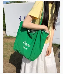 Escena exterior de una persona con un bolso verde vivo, letras blancas y una abertura amplia