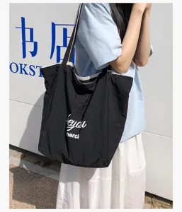 Escena urbana de una persona con bolso de tela negro y letras blancas llevado al hombro