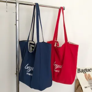 Dos bolsas tote de lona, azul marino y rojo, con asas a rayas, colgadas una junto a la otra