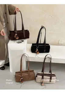 Four suede bags in brown, black, coffee, and beige are shown with straps and wooden charms.