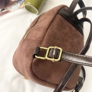Close-up of a brown faux suede bag with a dark leather strap and gold-tone buckle
