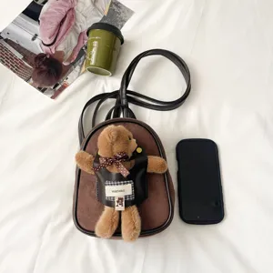 Overhead view of a brown suede mini bag with a plush bear, dark trim, and dual shoulder straps