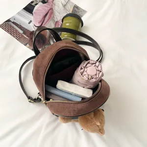 Close-up of the open brown bag showing its zippered compartments and neatly packed small items