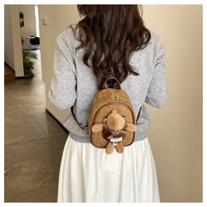 Rear view of a model wearing a brown suede-look mini backpack with a plush bear and checked ribbon