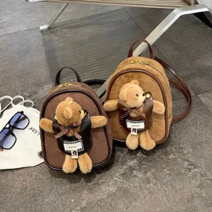 Small suede-look backpacks in dark brown and camel, each with a teddy bear plush charm