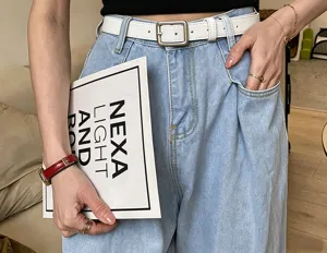 Nahaufnahme: hellblauer Jeansbund, weißer Gürtel mit Metallschnalle, Hand in der Tasche