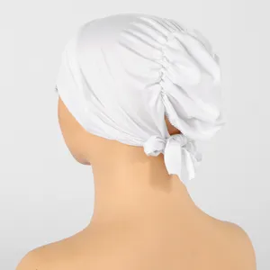 Vue arrière d’un bonnet blanc en maille extensible, avec des plis froncés et un lien noué