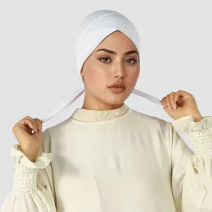 Couvre-chef blanc extensible, croisé sur le front, avec liens tenus par le modèle sur fond gris