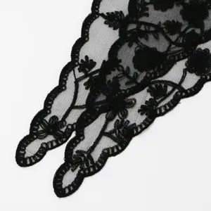 Close-up of black floral embroidered mesh lace with winding vines and a scalloped stitched edge