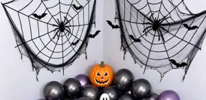Detail of two black spiderweb decorations with spider and bat accents on a white wall