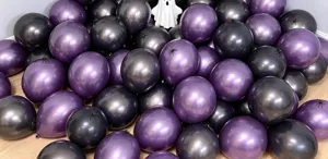 Close-up of glossy purple and black balloons with spider accents and a white ghost prop