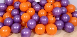 Close-up of glossy orange and purple Halloween balloons, with small black spider decorations