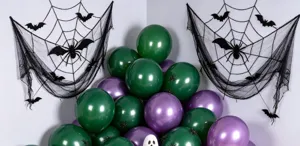 Halloween display with green and purple metallic balloons, black spiderweb fabric, bats and a spider