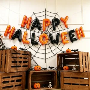 Orange and black foil letter balloons spelling HAPPY HALLOWEEN above pumpkins and wooden crates