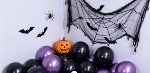 Halloween display with glossy black and purple balloons, a pumpkin lantern, bats, spiders, and web