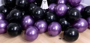 Close-up of glossy black and purple balloons arranged with small Halloween ghost and spider props