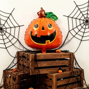 Halloween scene with an orange smiling pumpkin foil balloon, green leaf, and black spiderweb props