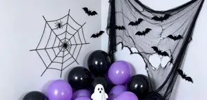 Halloween display with a spiderweb, bat cutouts, black gauze, purple balloons and a white ghost
