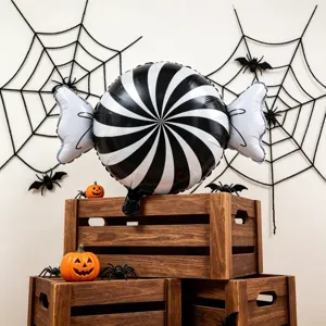 Black-and-white spiral foil balloon displayed among spiderwebs, toy spiders and pumpkin props