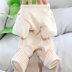 Close-up of an ivory four-leg pet jumpsuit with striped cuffs, held over a gray sofa