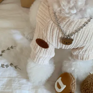 Gros plan sur le tricot côtelé beige, avec col, bordures de manches et pendentif ourson