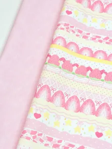 Close-up of plain pink cotton beside strawberry cake print with berries, hearts and pastel stripes