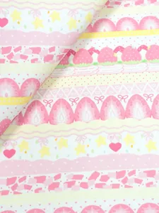 Close-up of folded fabric with pink and yellow stripes, strawberries, stars, hearts and bows
