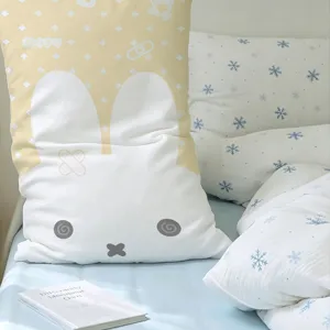 White and beige rabbit-shaped long cushion cover with a cute cartoon face, displayed on a bed